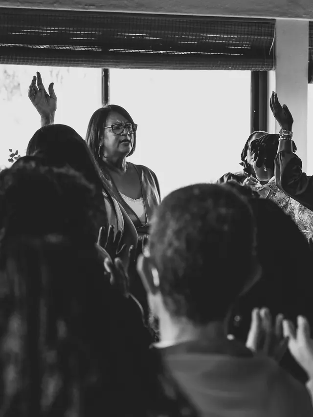 Women at a Fruitfulness Initiative gathering, hands raised in worship